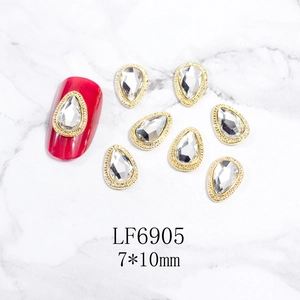 Primer plano de pedrería para uñas en forma de gota con borde de metal dorado texturizado