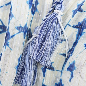 Dettaglio macro del motivo a stelle tie-dye blu su tessuto bianco con righe dorate
