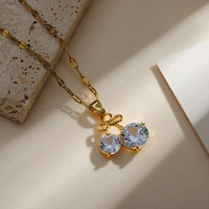 Macro detail of cherry pendant with clear round crystals and golden bow tie link