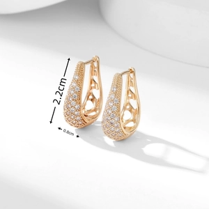 Detail view of U-shaped gold earrings with paved zircons and hollow heart structure