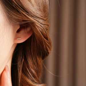 Close-up of a delicate gold-plated geometric stud earring with shimmering tiny crystals