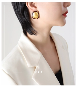 Close-up of vintage textured gold square earring with dark border on model