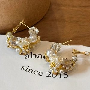 Detailed macro view of vintage flower earrings with pearls and crystals on gold C-shaped rings