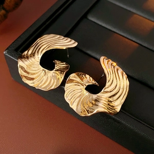 Detailed macro view of gold spiral earrings with ripple texture on black leather