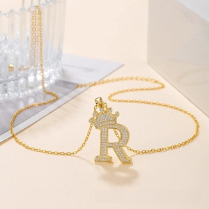 Detail of gold crown letter R pendant with sparkling pavé cubic zirconia setting