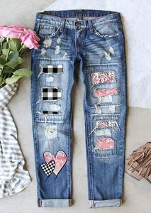 Détail du jean bleu délavé avec cœur pailleté rose et empiècements en patchwork à carreaux