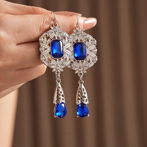 Detailed view of vintage silver drop earrings with blue sapphire stones and hollow patterns
