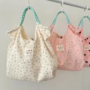 Detail view of cartoon rabbit embossed tote bags in seersucker fabric with woven handles