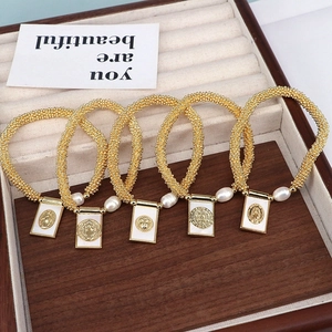 Detailed shot of gold beaded religious bracelets with shell pearls and enamel charms