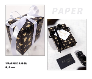 Detail of black gift wrapping paper featuring gold foil heart and crown patterns