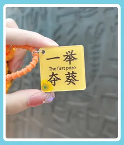 Detailed view of the yellow acrylic tag on a crochet keychain with sunflower motif