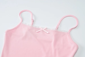 Detail of pink ribbed tank top featuring delicate white lace trim and a small center bow