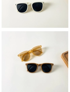 Flat lay of foldable kids sunglasses in ivory, tea brown and matte coffee finishes