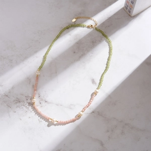Peridot and pink opal beaded necklace with freshwater pearls on white marble background
