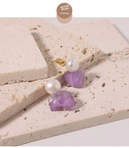 Detailaufnahme von Ohrringen mit Süßwasserperlen und Amethyst auf Naturstein