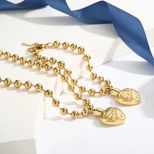 Detail view of golden ball chain necklaces with heart pendants and a blue silk ribbon
