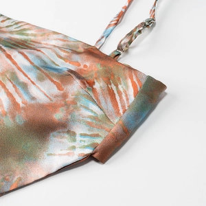 Macro detail of silk tie-dye fabric texture and adjustable thin strap on women top