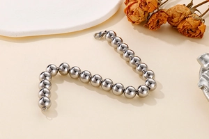 Detail shot of silver bead bracelet with lobster clasp on an elegant floral backdrop