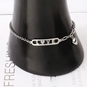 Vue détaillée du bracelet en acier argenté avec plaque LOVE ajourée et pendentif cœur