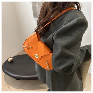 Detail of bright orange patent leather shoulder bag with golden metallic swivel lock