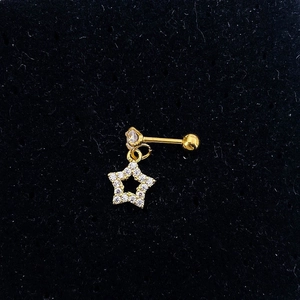 Macro shot of gold star earring with clear zircon inlay on a black background