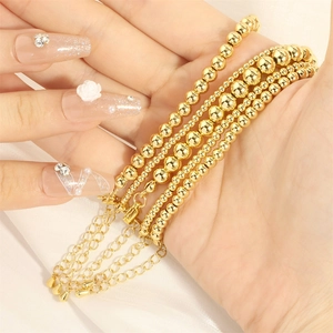 Detail of multilayer gold bead bracelets featuring adjustable clasp on soft white fabric