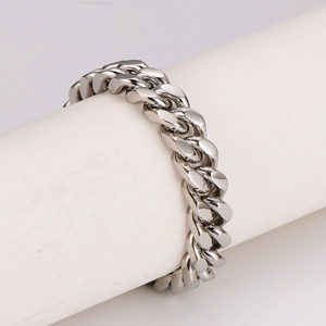 Polished silver stainless steel Cuban link bracelet displayed on a white cylindrical stand