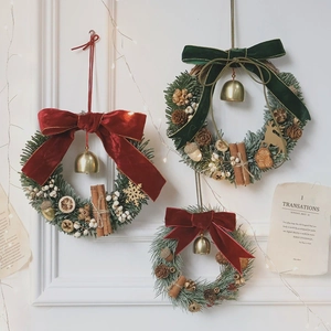 Handmade Christmas wreath with pine needles, velvet bow, golden bells and dried fruit