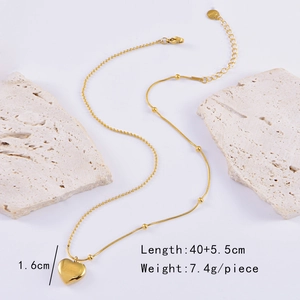 Detailed view of golden heart pendant necklace on white textured stone display
