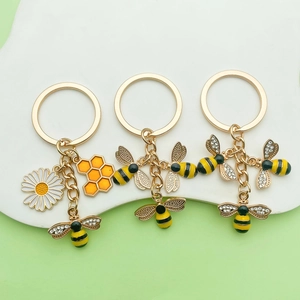 Detail of bee and daisy keychains featuring honeycombs with rhinestones and enamel finish