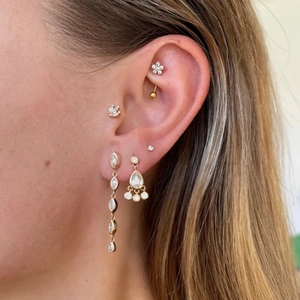 Detail of gold drop earrings and marquise opal studs on a model for a layered jewelry look