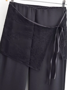 Detail of black satin pants featuring intricate lace wrap-around ties and waist texture