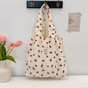 Vue détaillée du sac cabas en velours côtelé beige avec imprimé fraises au mur