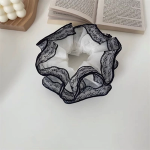 Vue détaillée d'un chouchou blanc avec bordure en dentelle noire sur fond blanc