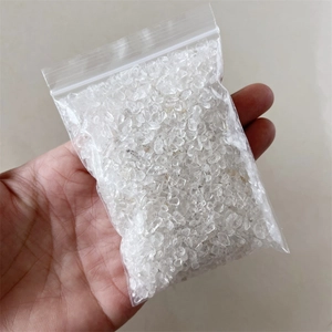 Close-up of clear quartz crystal chips in a transparent plastic bag held by hand