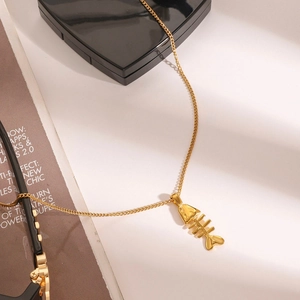 Gros plan d'un collier pendentif arête de poisson doré sur une fine chaîne élégante
