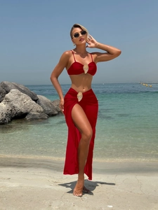 Three-piece red bikini set with gold shell buckles and a matching side-slit wrap skirt