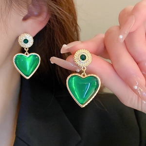 Close-up of vintage green heart earrings with gold trim and crystal-encrusted round studs