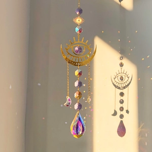 Detail of golden moon suncatcher with purple crystals casting rainbow light on wall