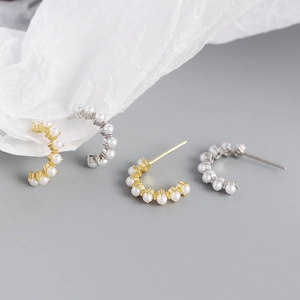 Detailed view of C-shaped hoop earrings featuring multiple small pearls in gold and silver