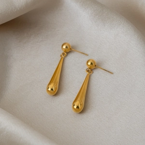 Vue détaillée des boucles d'oreilles goutte d'eau plaquées or 18 carats sur de la soie