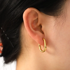 Minimalist gold U-shaped twisted hoop earrings shown on model with high metallic luster