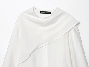 Close-up of white blouse neckline with elegant asymmetric drapes and textured fabric