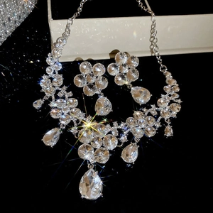 Close-up of sparkling crystal flower and waterdrop pendant jewelry set on black surface