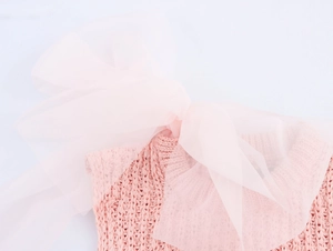 Detail of pink knitted top featuring a large organza bow on the shoulder neckline