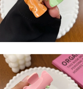 Macro detail of mini candy-colored hair claws in pink, orange, and green plastic