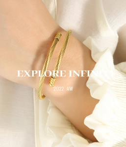 Close-up of golden twist rope open bangle with textured metal caps on white fabric
