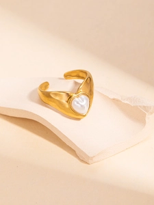 Macro detail of adjustable gold ring featuring a white heart inlay and hammered texture