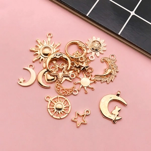 Golden celestial DIY pendants featuring sun, moon, and star charms on pink background