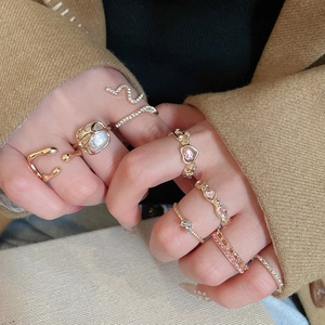 Detail of stacked gold heart and snake rings with crystals and pearls on hand
